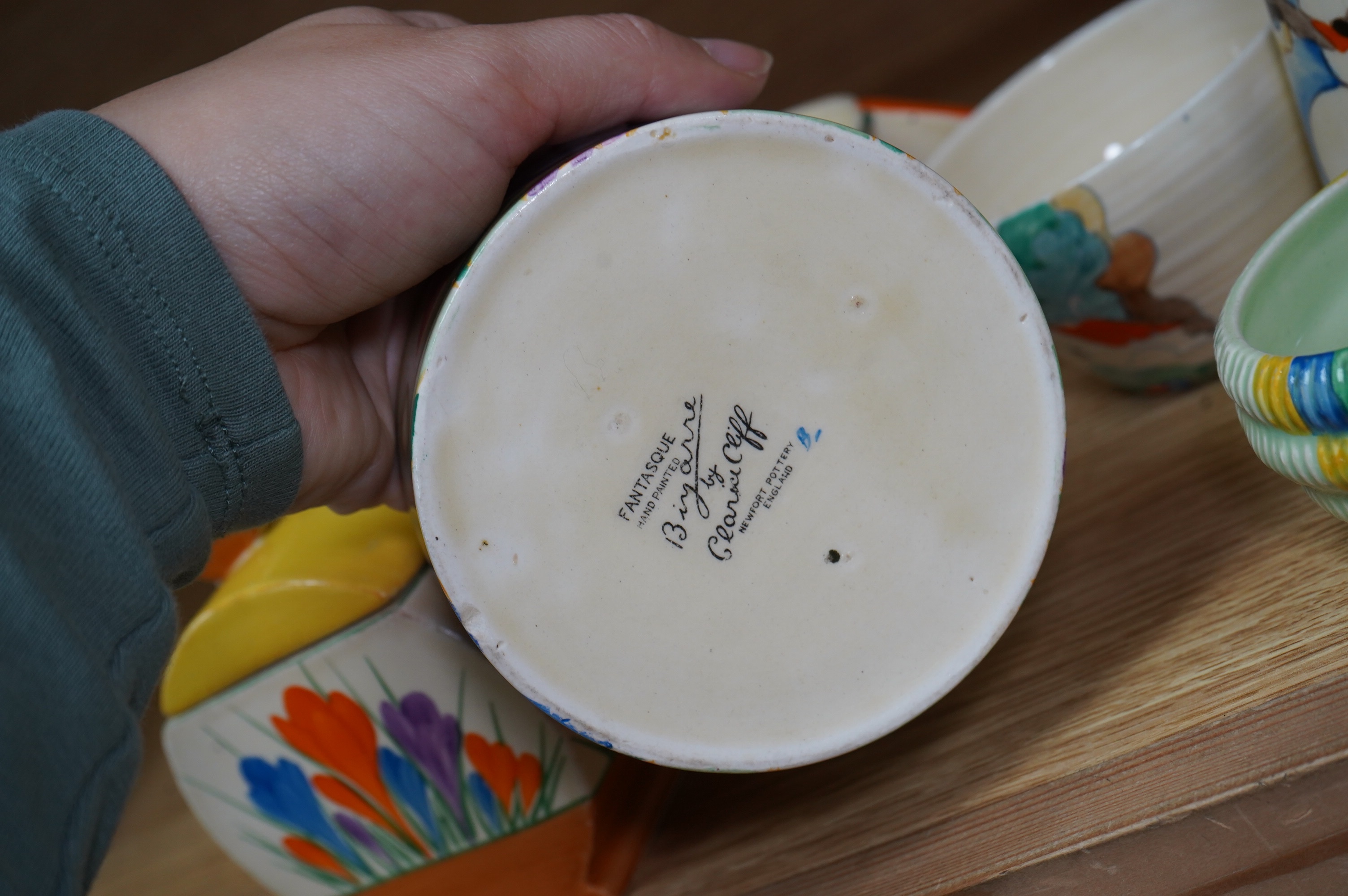 A collection of Clarice Cliff including; a Tiger Tree conical sugar sifter (c.1937), a cup marked 5799, a two handled pomegranate cup, a bowl, two plates, a mustard pot, etc. Condition - fair